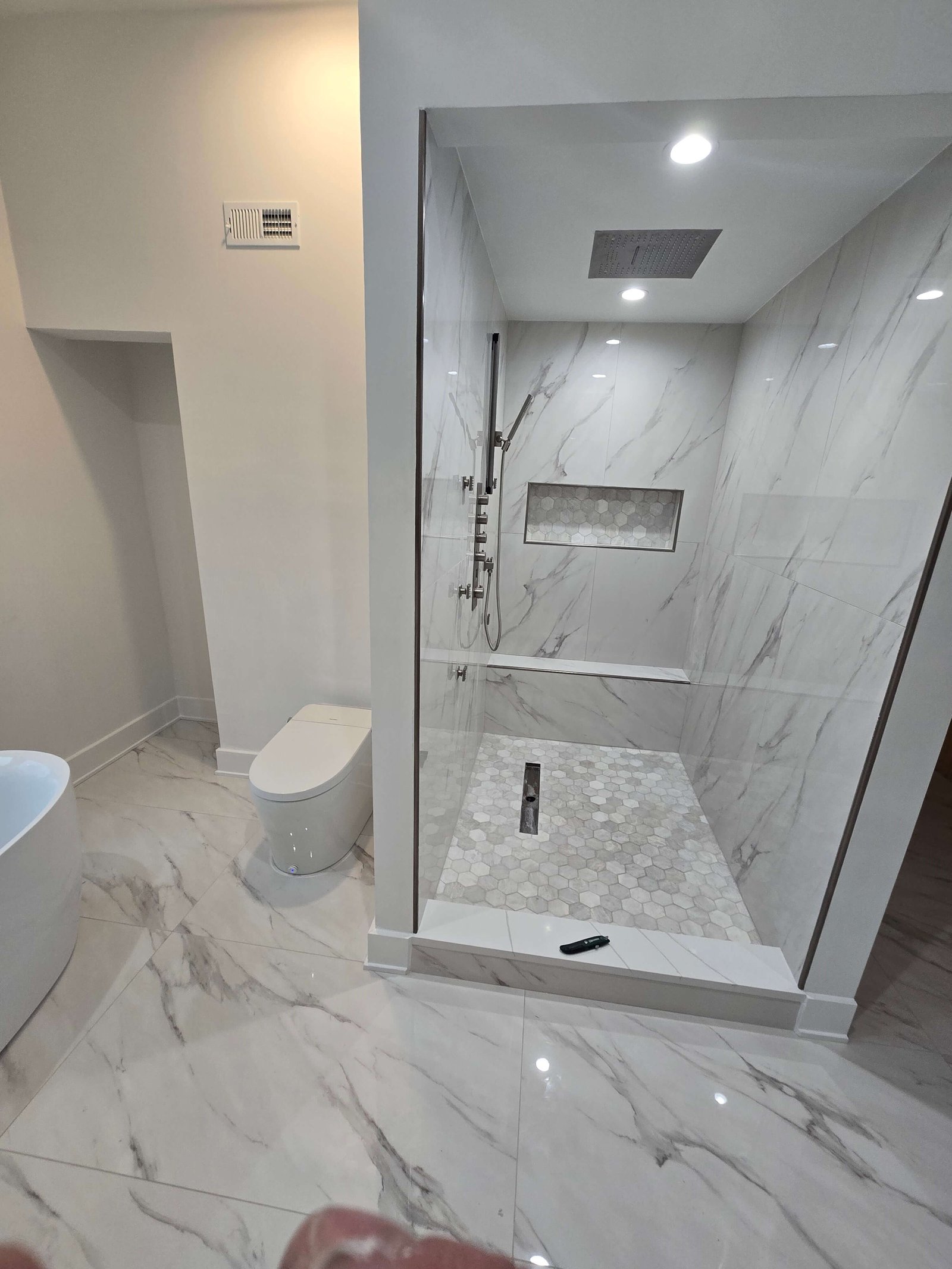 Completed custom tile shower with hex floor and niche